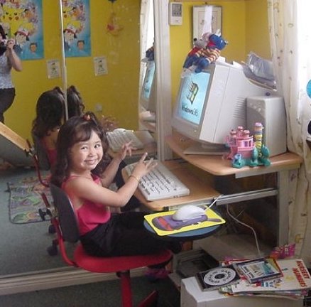 young girl sat at a computer desk
